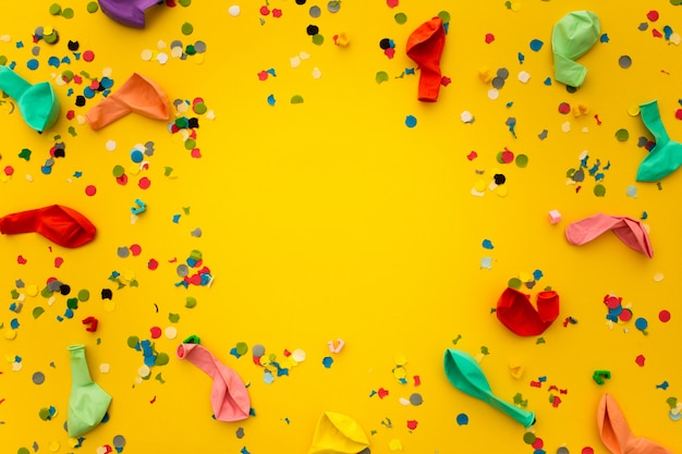 Вечеринка с остатками конфетти и разноцветными шариками на желтом