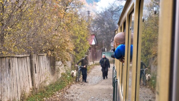 Passengers leaned out of the windows of the steam train Mocanita moving through a village