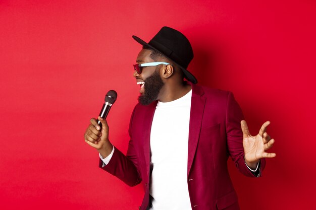 Passionate black male singer performing against red