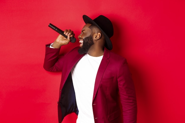 Free photo passionate black male singer performing against red