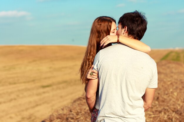 Passionate girl kissing her boyfriend in the field