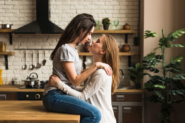 Passionate lesbian young couple loving each other in the kitchen