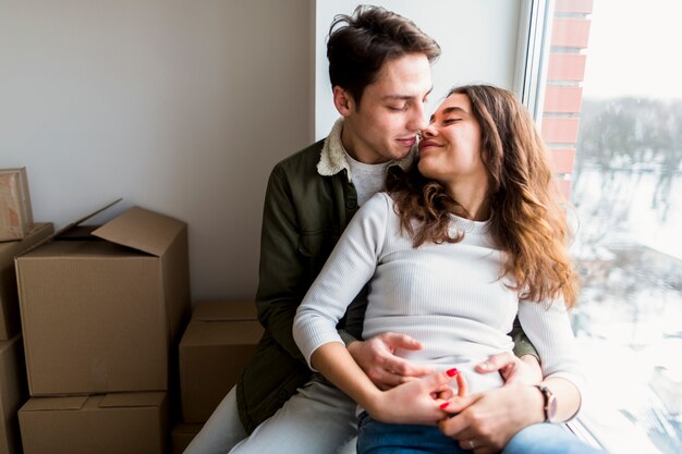 Passionate young couple sitting near the window in their new house