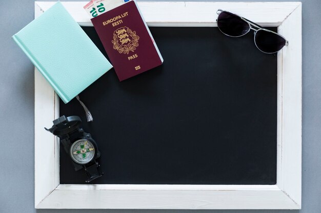 Passport and tourist supplies on blackboard