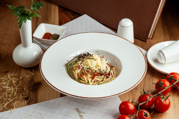 Foto gratuita pasta alla bolognese con formaggio pomodori sale e pepe sul tavolo