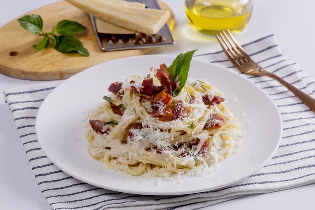 Паста карбонара. спагетти с беконом, парселем и пармезаном. паста карбонара на белой тарелке с пармезаном. итальянская еда.