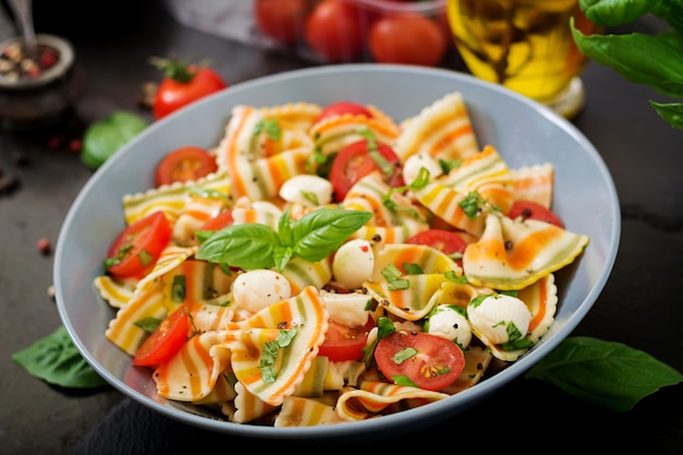 Insalata di farfalle di pasta colorata con pomodori, mozzarella e basilico.
