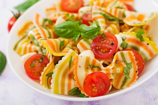 Pasta colored farfalle salad with tomatoes, mozzarella and basil.