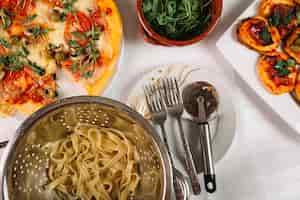 Free photo pasta and cutlery near pizzas