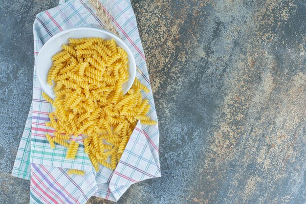 ひっくり返ったボウルから落ちてくるパスタ、大理石の表面。