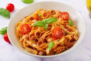 pasta fettuccine bolognese with tomato sauce in white bowl.