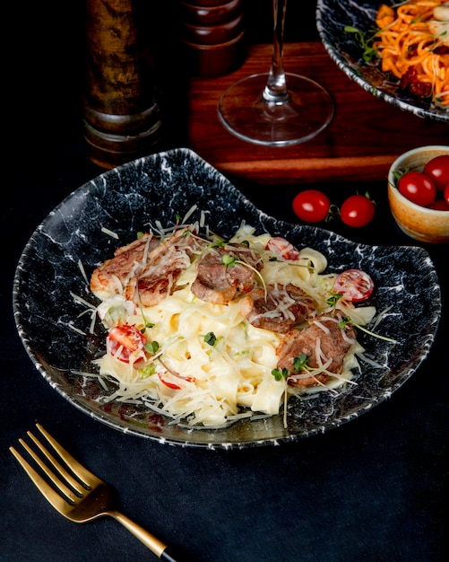 Foto gratuita fettuccine di pasta con vista laterale di carne e pomodoro