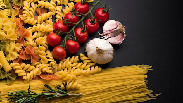 Pasta and ingredients for cooking on dark backdrop