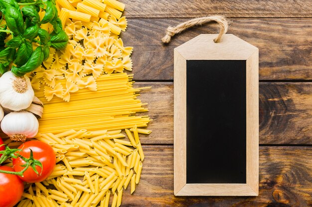 Pasta ingredients near blank chalkboard