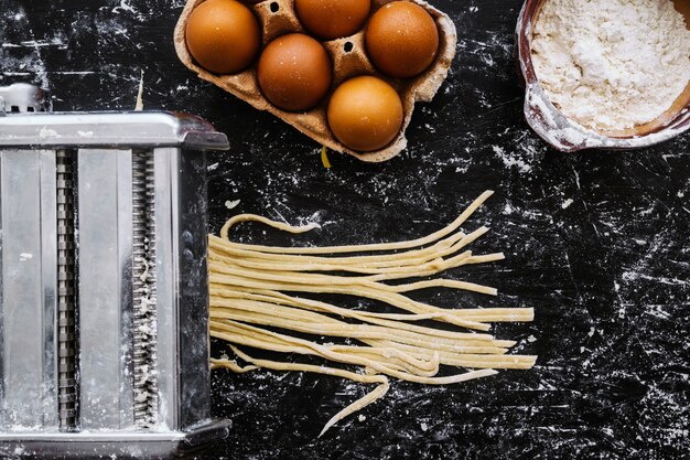 Pasta machine cutting dough near ingredients