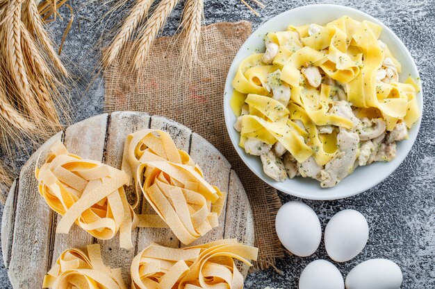 Pasta meal with eggs, cereals, raw pasta, wooden board in a plate