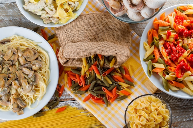 Pasta meals in plates with raw pasta, mushrooms