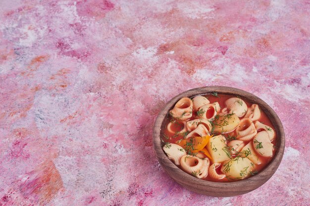 Pasta soup in tomato sauce in a wooden cup.