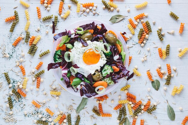 Pasta and spices around salad with fried egg