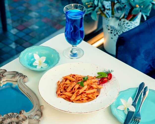 Pasta in tomato sauce and a glass of blue drink