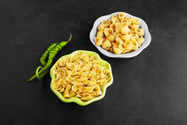 Pasta varieties on black in blue and green bowles.