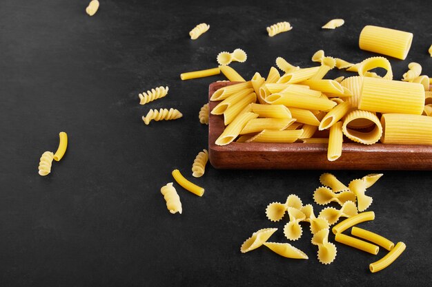 Pasta varieties on black on a wooden board.