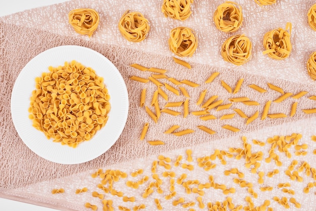 Free photo pasta varieties on pink tablecloth.