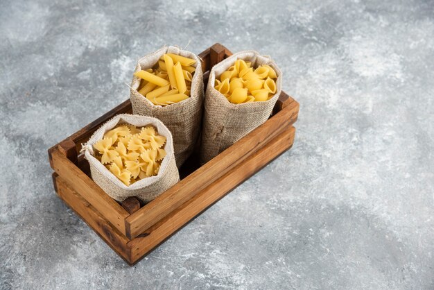 Pasta varieties in rustic basket inside a wooden tray.