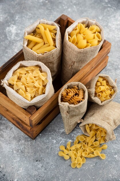 Pasta varieties in rustic basket inside a wooden tray.