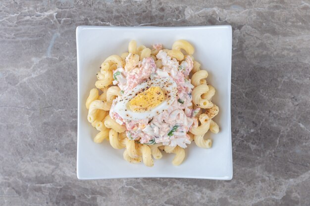 Pasta with boiled eggs in white bowl.