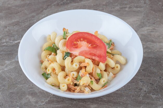 白い皿にさいの目に切った野菜のパスタ。