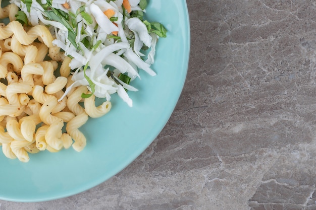 Pasta with fresh salad and egg on blue plate.