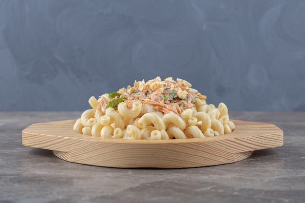 Free photo pasta with fresh salad on wooden plate.