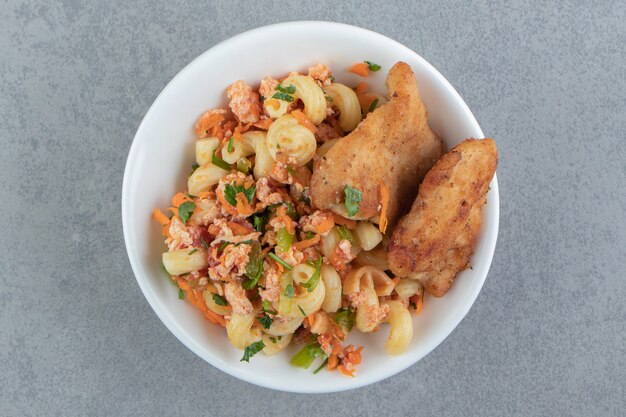 Pasta with fried chicken in white bowl.