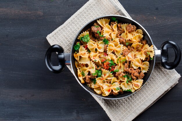 Pasta with meat in a pan on wooden table