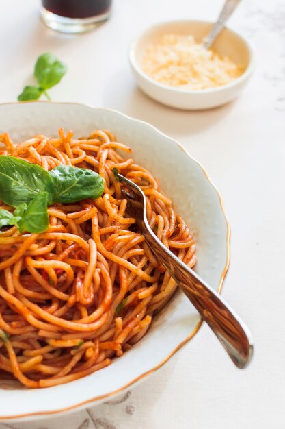 Pasta with tomato sauce and basil on ceramic plate with fork