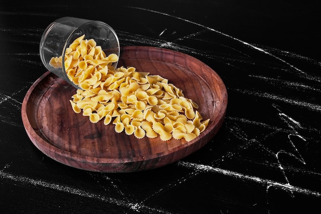 Pasta on a wooden platter out of a glass cup