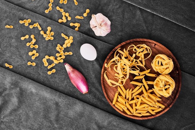 Foto gratuita pasta in un piatto di legno con verdure.