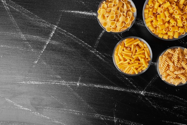 Pastas in glass cups in black table. 