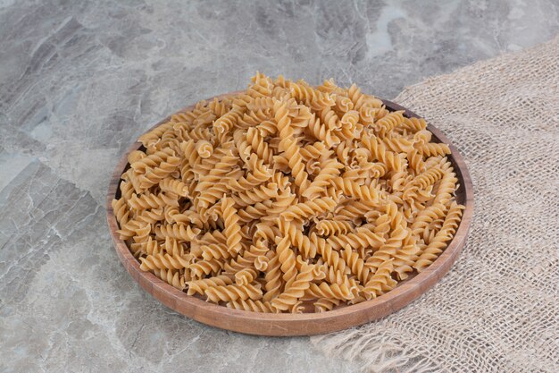 Pastas isolated in a rustic wooden plate on the marble