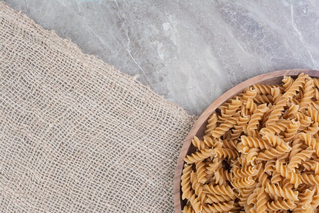 Pastas isolated in a rustic wooden plate on the marble