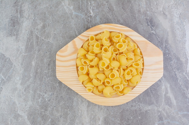 Pastas isolated in a rustic wooden plate on the marble