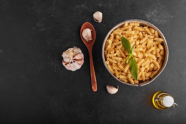 Pastas in a metallic bowl with ingredients around.