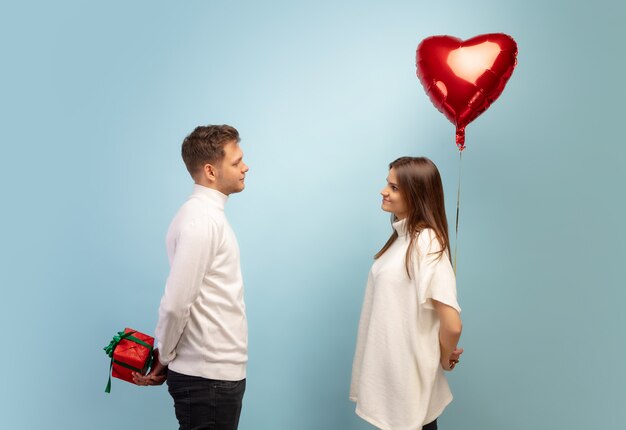 Pastel. Beautiful couple in love on blue studio background. Saint Valentine's Day, love, relationship and human emotions concept. Copyspace. Young man and woman look happy together.