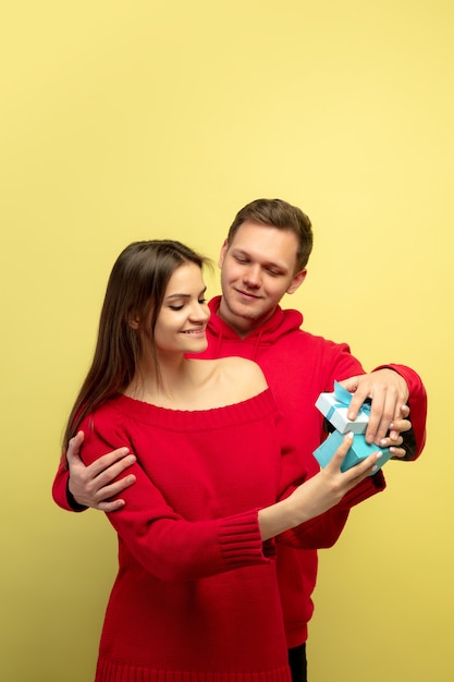 Pastel. Beautiful couple in love on yellow studio background. Saint Valentine's Day, love, relationship and human emotions concept. Copyspace. Young man and woman look happy together.