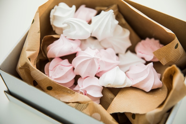 Free photo pastel colored zephyrs wrapped in the paper inside the open box