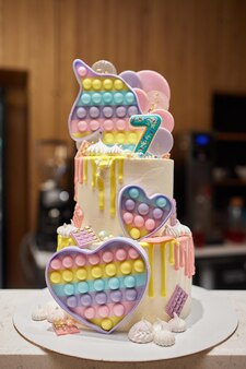 스프링클 장식과 양초가 있는 파스텔 핑크 베이비 생일 케이크 7년 번호
