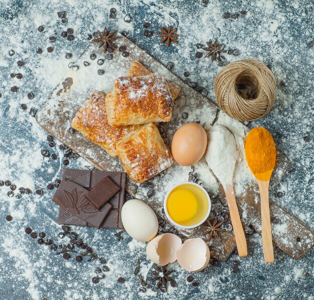 Pastries with flour, chocolate, spices, eggs, thread top view on concrete and cutting board