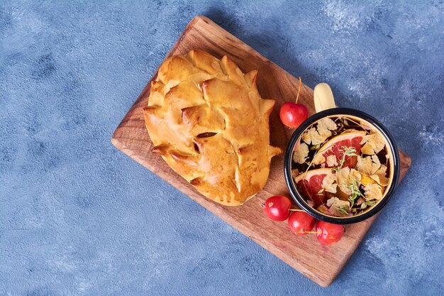 Pastry bun with herbal tea on a wooden board on blue