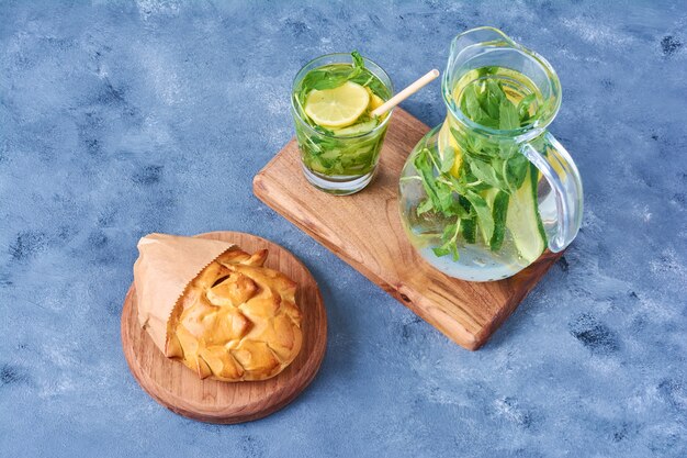 Panino di pasticceria con mojito su una tavola di legno sul blu